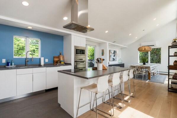 A modern kitchen with a central island, stainless steel appliances, and a dining area with bar stools.