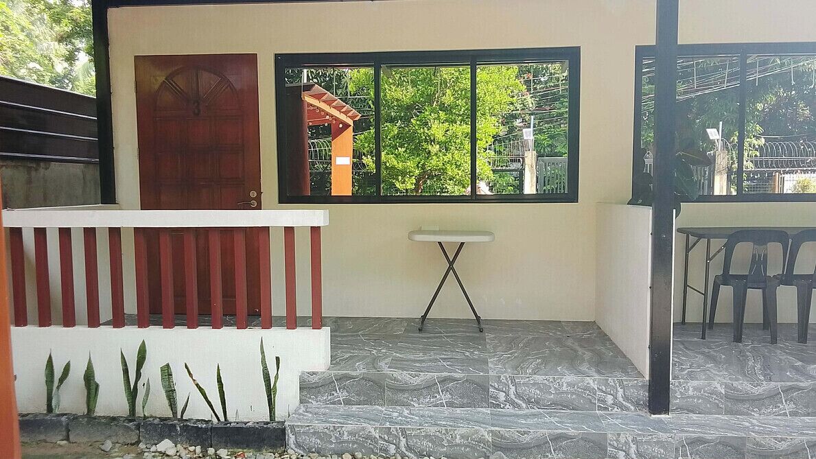 A room with a door, a window, a small table, and a seating area with chairs.