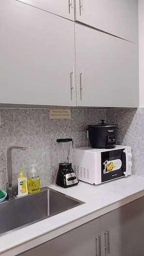 A kitchen with a sink, a blender, a slow cooker, and a microwave.