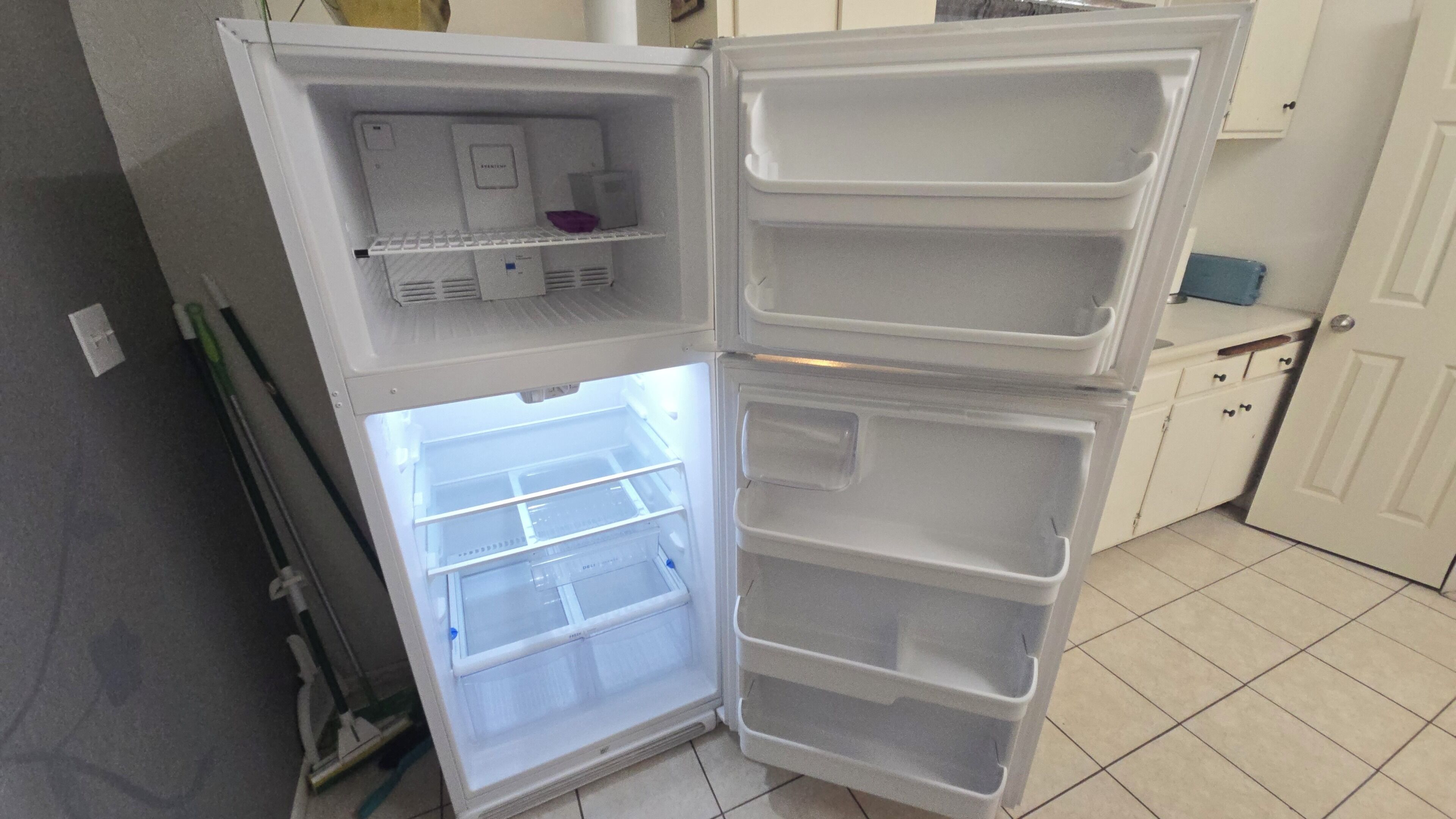 Un réfrigérateur ouvert, doté de plusieurs étagères et d’un compartiment congélateur.