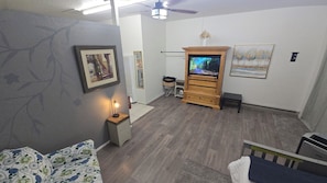A living room with a television, a sofa, a small table with a lamp, and a fireplace.
