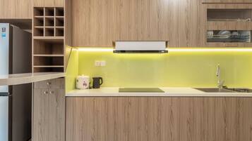 Una cocina moderna con armarios de madera, horno empotrado, lavaplatos y encimera con hervidor y cafetera.