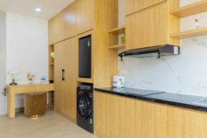 A modern kitchen with wooden cabinets, a built-in washing machine, a microwave, and a stainless steel countertop. - LANA SEA HOTEL & APARTMENT (An Thoi)