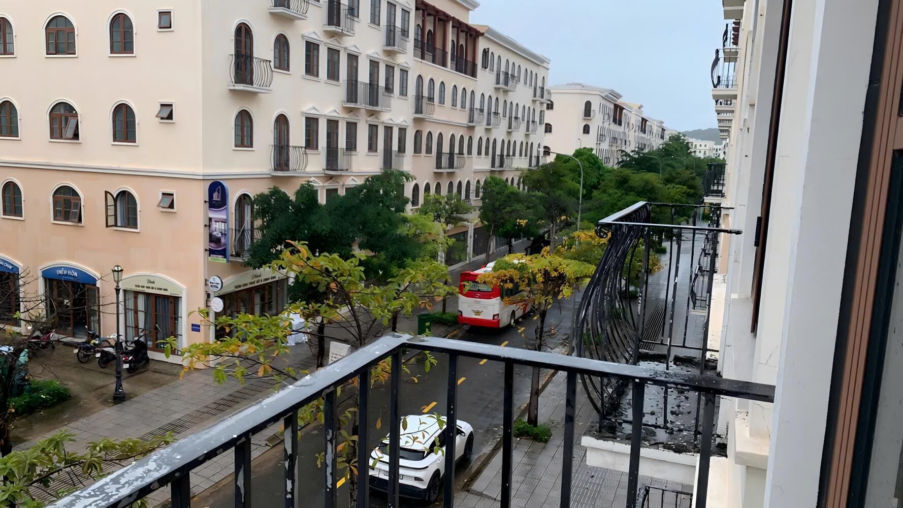 A balcony overlooking a street with parked vehicles and buildings.