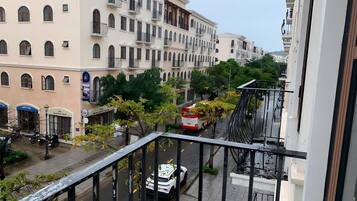 A balcony overlooking a street with parked vehicles and buildings.