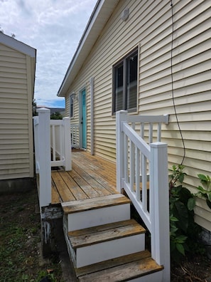 A wooden deck leading to a house with a white railing and a blue door. - Charming 1-bedroom apartment with AC in Brigantine (Brigantine)