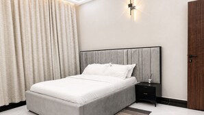 A modern bedroom with a bed, nightstand, and a wall-mounted light fixture.