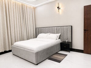A modern bedroom with a bed, nightstand, and a wall-mounted light fixture.