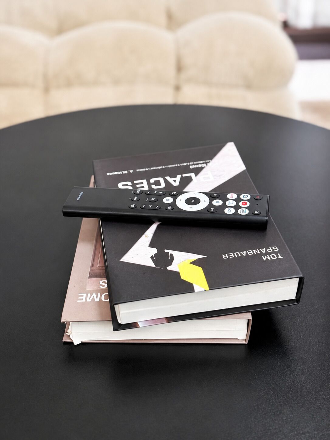 Ein schwarzer Tisch mit zwei Büchern und einer Fernbedienung darauf.