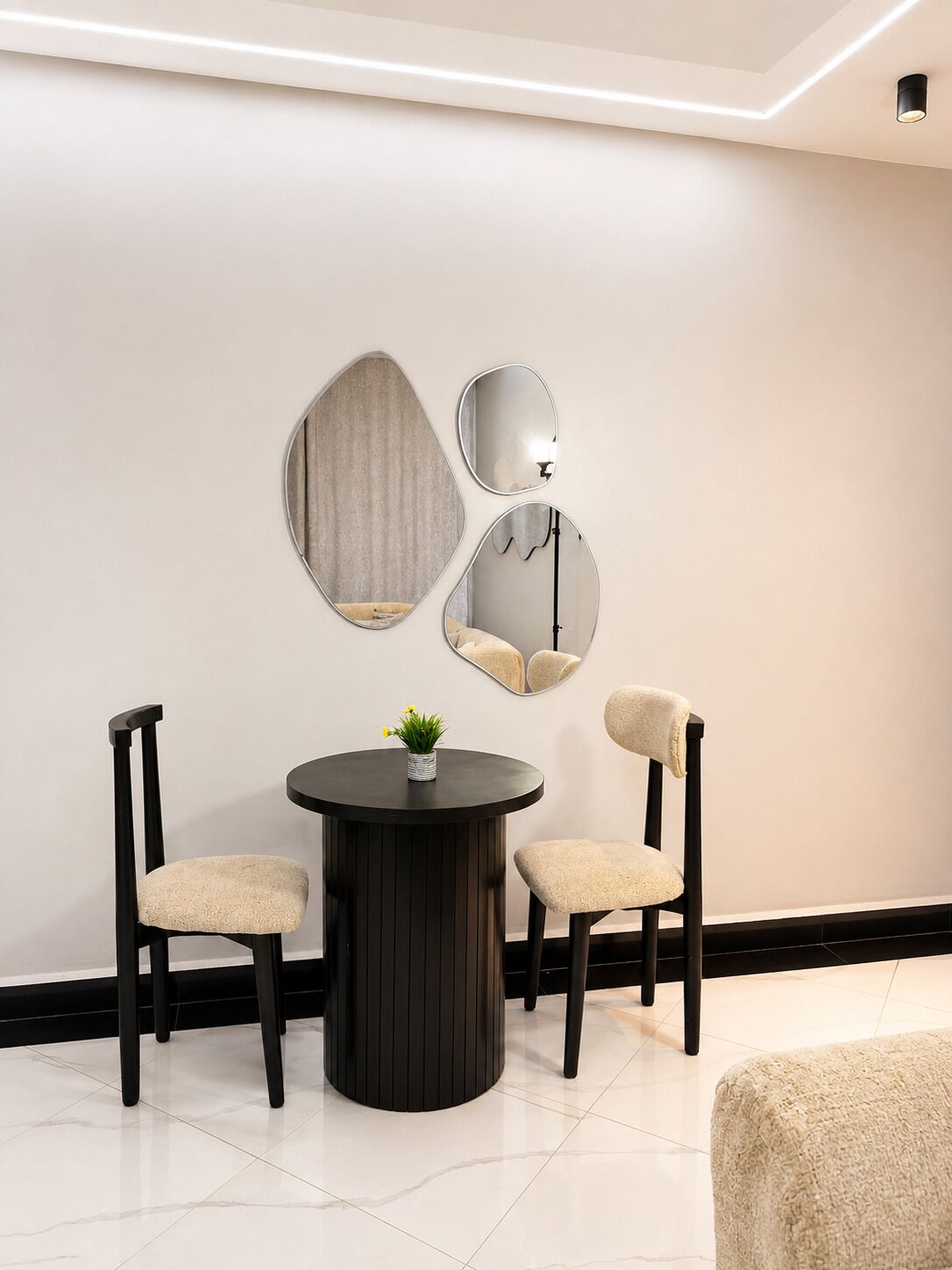 A modern room with a round table, two chairs, and three wall-mounted mirrors.