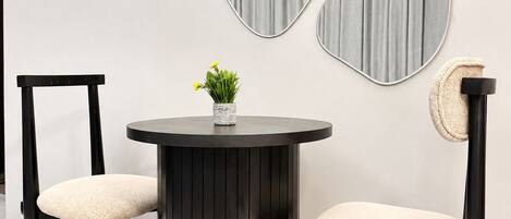 A modern interior with a round table, two chairs, and decorative wall mirrors.
