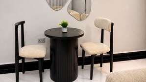 A modern interior with a round table, two chairs, and three wall-mounted mirrors.