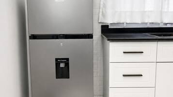 A kitchen with a stainless steel refrigerator, a water dispenser, and white cabinetry.