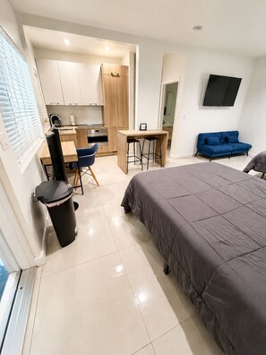 A modern hotel room with a large bed, a kitchenette, a small dining area, and a TV mounted on the wall. - Beautiful studio with 2 beds- Midtown (Miami)