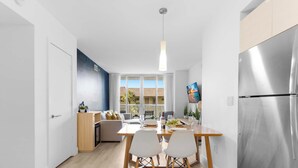 A modern kitchen with a dining area, large windows, and a stainless steel refrigerator. - Cozy 1BR- Bay View - Resort Pool & Private Balcony (Hallandale Beach)