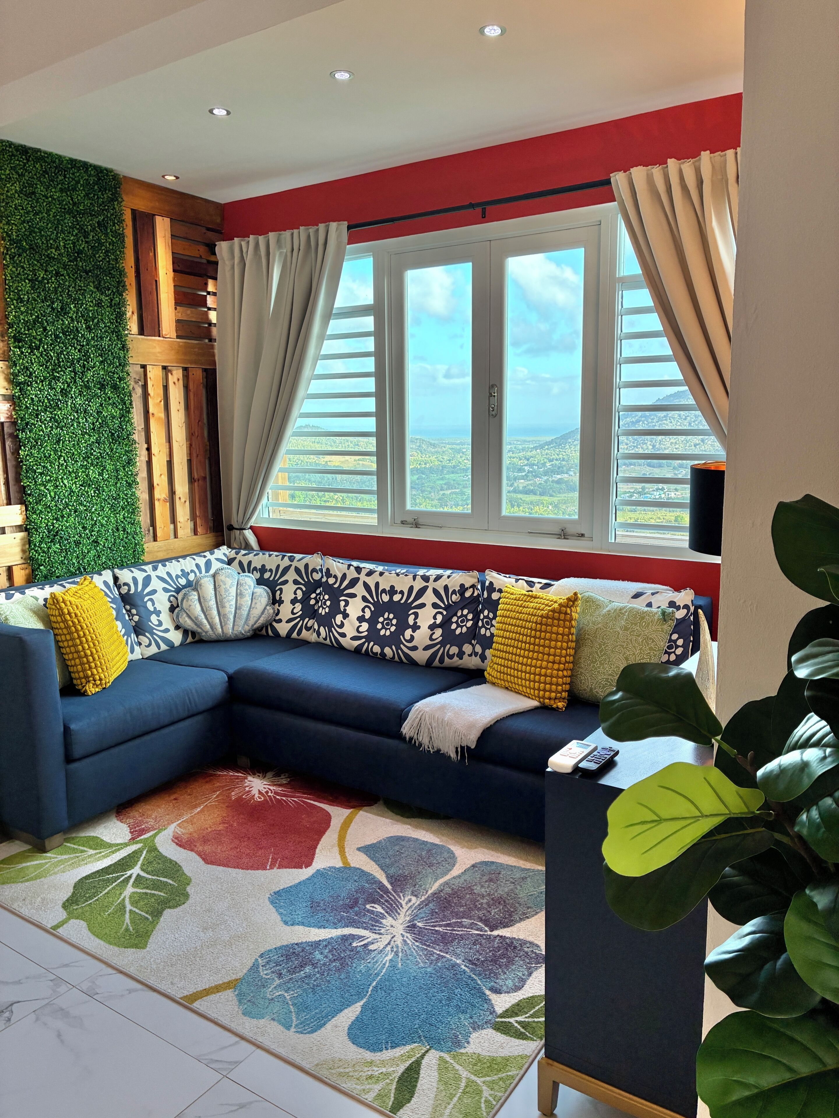 A living room with a sectional sofa, a patterned rug, a green wall, and a window with curtains.