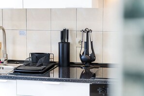 A kitchen with a black knife block, a black utensil holder, and a black tray. - GuestReady - Charming Getaway in Ribeira da Janela (Ribeira da Janela)