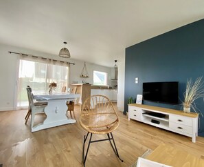 Ein modernes Wohnzimmer mit Essbereich, Fernseher und großem Fenster.