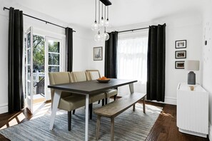 A dining area with a dark wooden table, beige chairs, a bench, and a bowl of fruit. - A Peaceful Home in the Heart of Napa Valley (Napa)