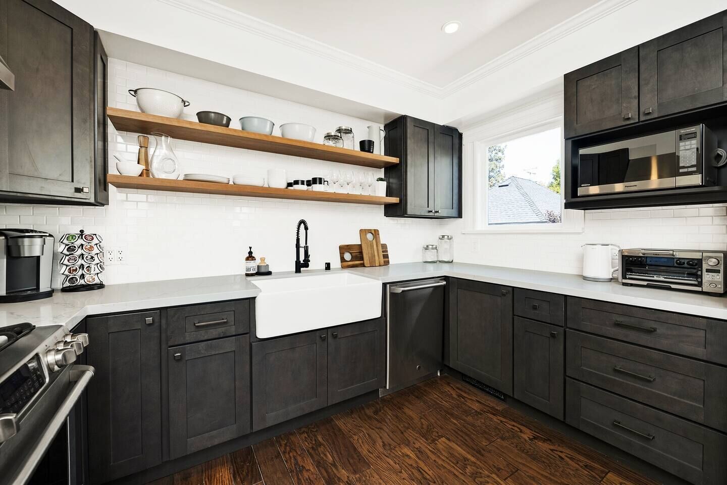 A modern kitchen with dark cabinetry, a white countertop, and a built-in oven.