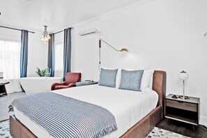 A modern hotel room with a large bed, a desk, a chair, and a bedside table with a lamp. - A Peaceful Home in the Heart of Napa Valley (Napa)