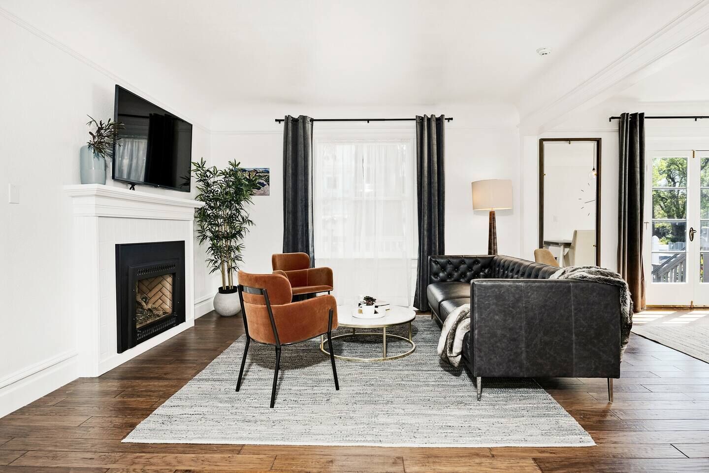 Een moderne woonkamer met een open haard, een bank, een salontafel en een groot raam met gordijnen.