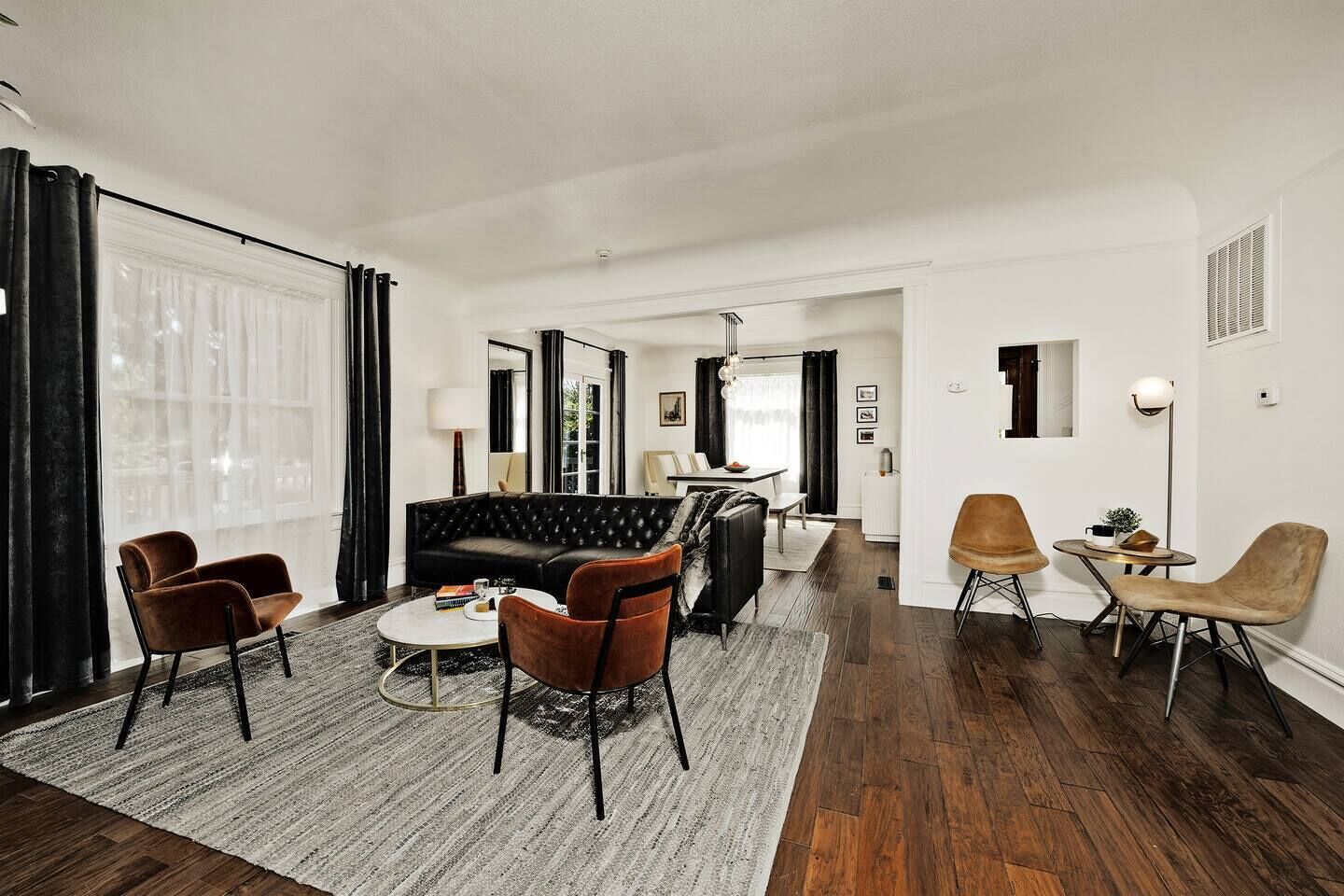 Een moderne woonkamer met een leren zwarte bank, bruine fauteuils en een salontafel.