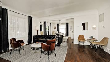 Een moderne woonkamer met een leren zwarte bank, bruine fauteuils en een salontafel.