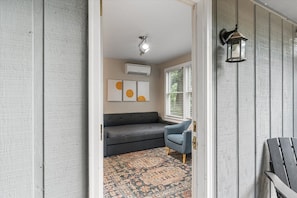 A hallway with a gray sofa, a patterned rug, and a blue chair.
