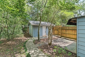 A backyard with a shed, a wooden fence, and a concrete path.