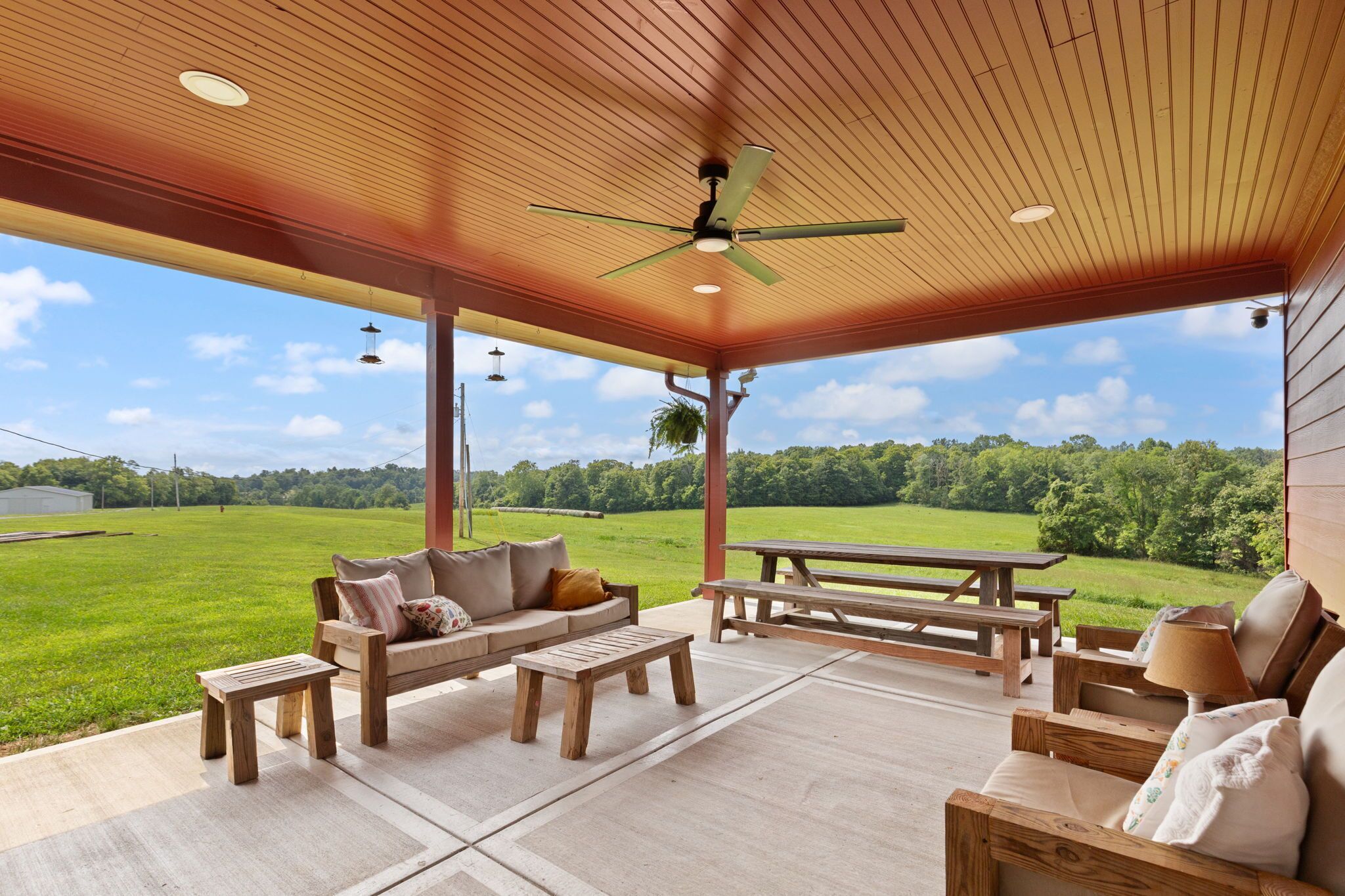 Un patio exterior con techo de madera, un sofá, una mesa y un banco.