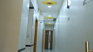 Un passadís amb una paret de marbre d'un costat, una porta de fusta al final i un sostre amb il·luminació empotrada i un detall en groc.