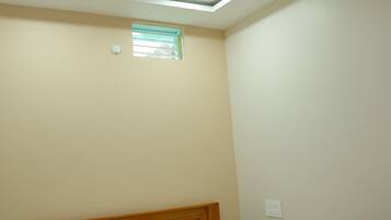 A bedroom with a bed, a ceiling fan, recessed lighting, a small window, and a wall-mounted light switch.