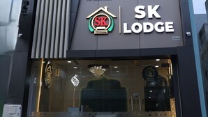 Un edifici modern amb un senyal SK Lodge ben visible, que presenta un logotip amb 'SK' vermell i una corona de llorer.