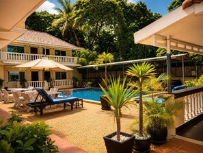 A pool area with lounge chairs and umbrellas, surrounded by potted plants and a wooden fence. - Abode Hotel Siem Reap (Siem Reap)
