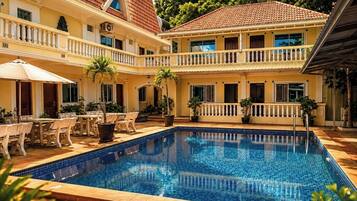 A two-story building with a swimming pool, outdoor seating, and a covered patio area.