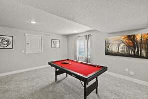 A pool table in a room with a door, a window with curtains, and a painting on the wall. - Spacious 5-bedroom house in beautiful Colorado Springs with AC (Colorado Springs)