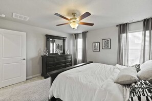 A bedroom with a bed, dresser, ceiling fan, and window with curtains. - Spacious 5-bedroom house in beautiful Colorado Springs with AC (Colorado Springs)