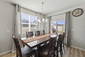 A dining area with a table, chairs, a chandelier, and a clock on the wall. - Spacious 5-bedroom house in beautiful Colorado Springs with AC (Colorado Springs)