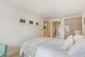 Ein Schlafzimmer mit einem großen Bett, einer Tür zu einem Badezimmer und drei gerahmten Bildern an der Wand.