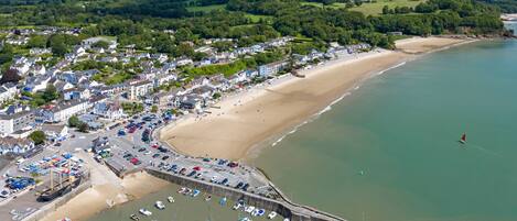 A coastal town with a sandy beach, a marina with numerous boats, and a fortified structure.