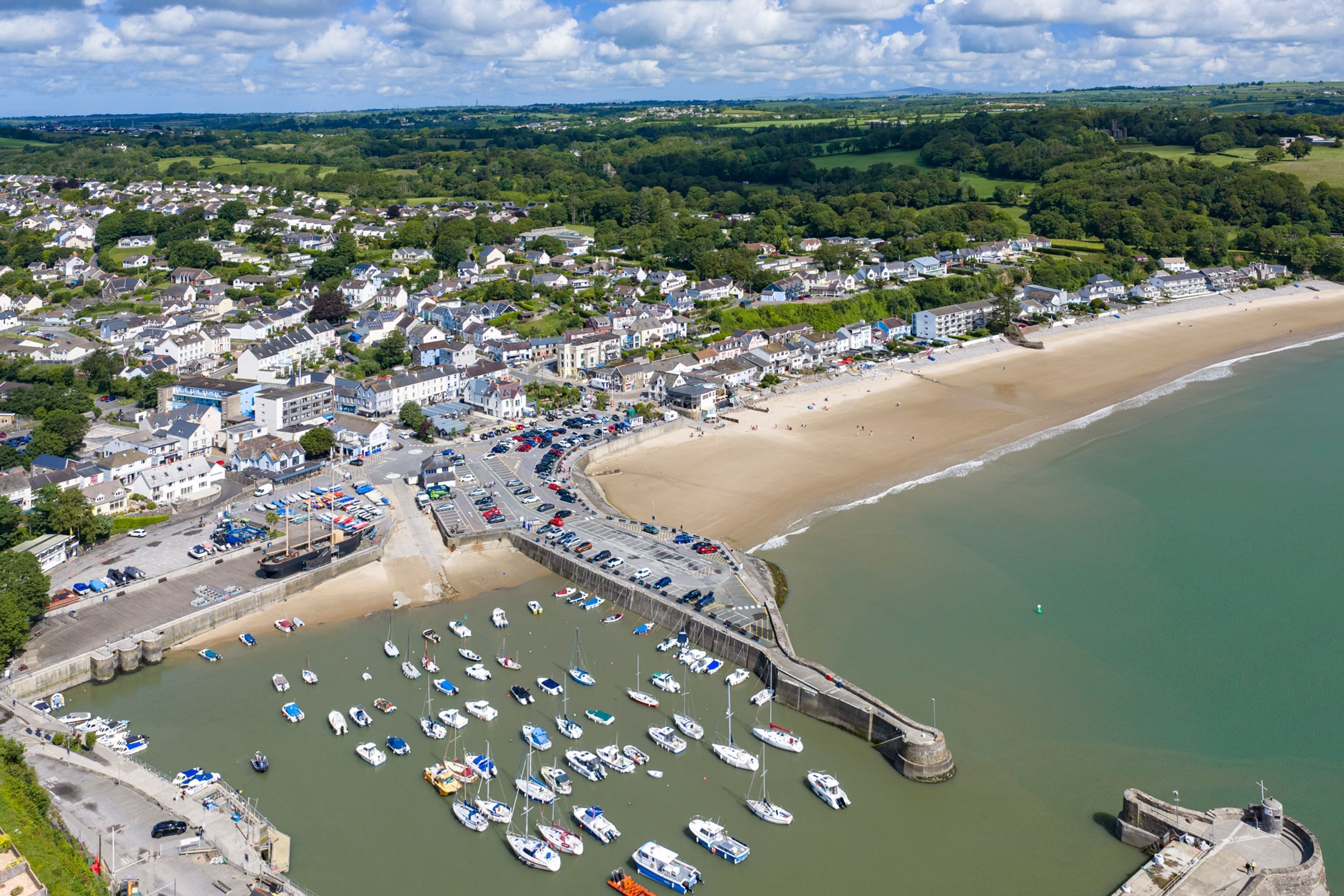 A coastal town with a marina, sandy beach, and residential buildings.