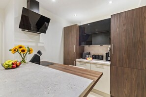 Eine moderne Küche mit Backofen, Mikrowelle und einem großen, schwarzen Fernseher an der Wand.