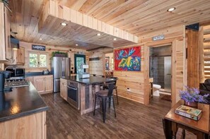 A wooden cabin interior with a kitchen, dining area, and a bathroom.