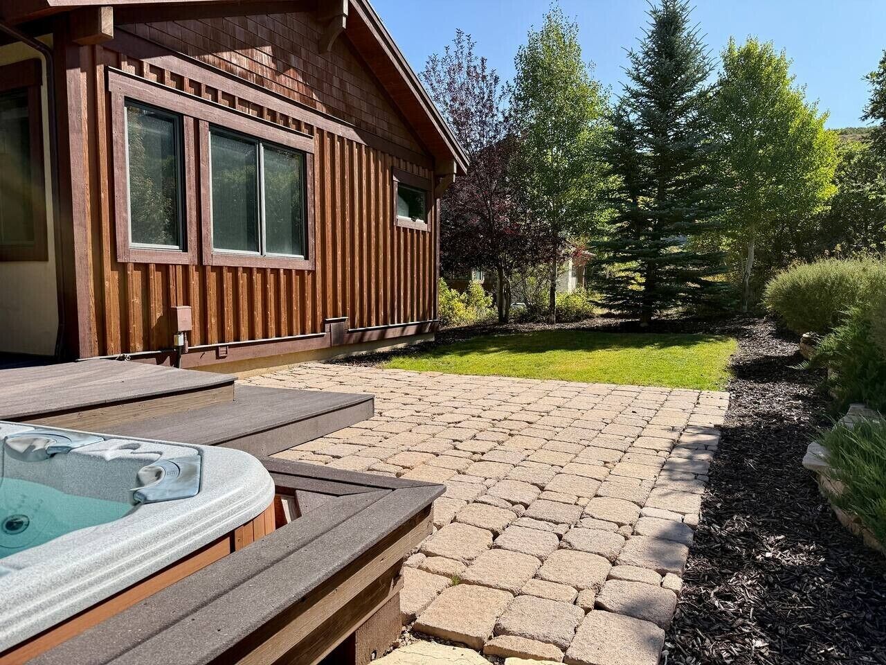 Een houten chalet met een jacuzzi en een terras.