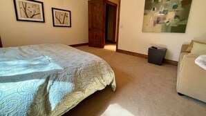 A bedroom with a bed, a door, a trash bin, and a painting on the wall. - Deer Valley Luxury Lodge | Shuttle, Hot Tub, Games (Park City)
