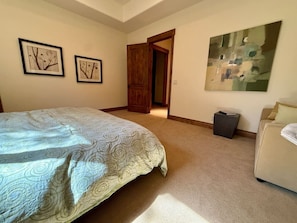 Ein Schlafzimmer mit Bett, einer Tür, einem Mülleimer und einem Bild an der Wand.