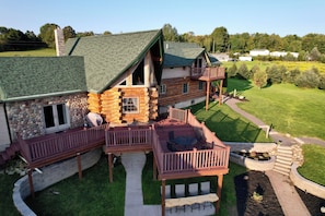 A log cabin with a deck and outdoor seating area. - Gorgeous Custom Built Log Home w/ Indoor Pool (Annsville)