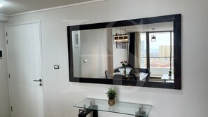 A bathroom with a large mirror, a glass vanity, and a view of the cityscape through the window.