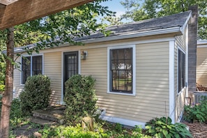 A single-story house with a front porch, a small front yard with shrubs, and a visible air conditioning unit.